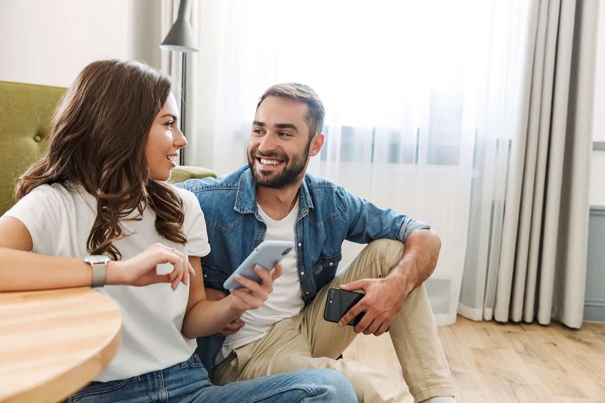 Couple happily using their repaired smartphones at home